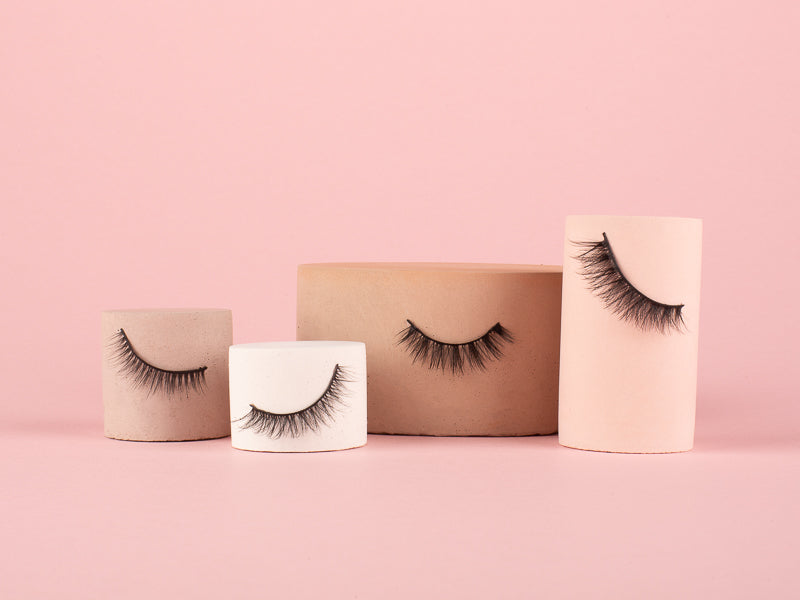Model holding pair of packaged wing it Silk System false vegan eyelashes in cream packaging