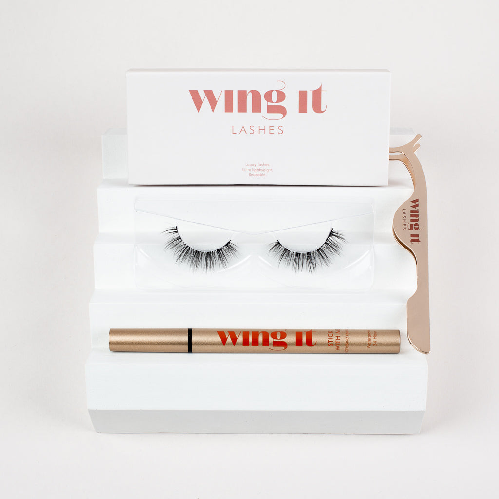Set of Wing It Cosmetics false eyelashes, adhesive eyeliner pen and golden lash applicator.