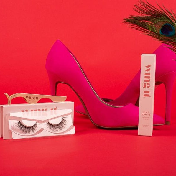 False lash set with pair of silk lashes, gold adhesive eyeliner and lash applicator and pink shoes.